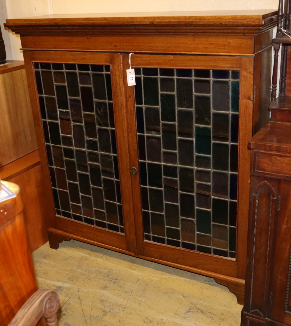 An Edwardian oak bookcase enclosed by stained leaded glass doors, W124cm, D.34cm, H.128cm